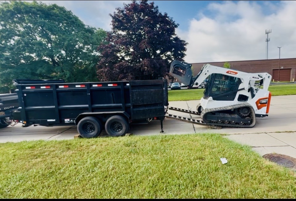 Dumpster Doll dump trailer and skid steer on a Livonia, Michigan job site during cleanup