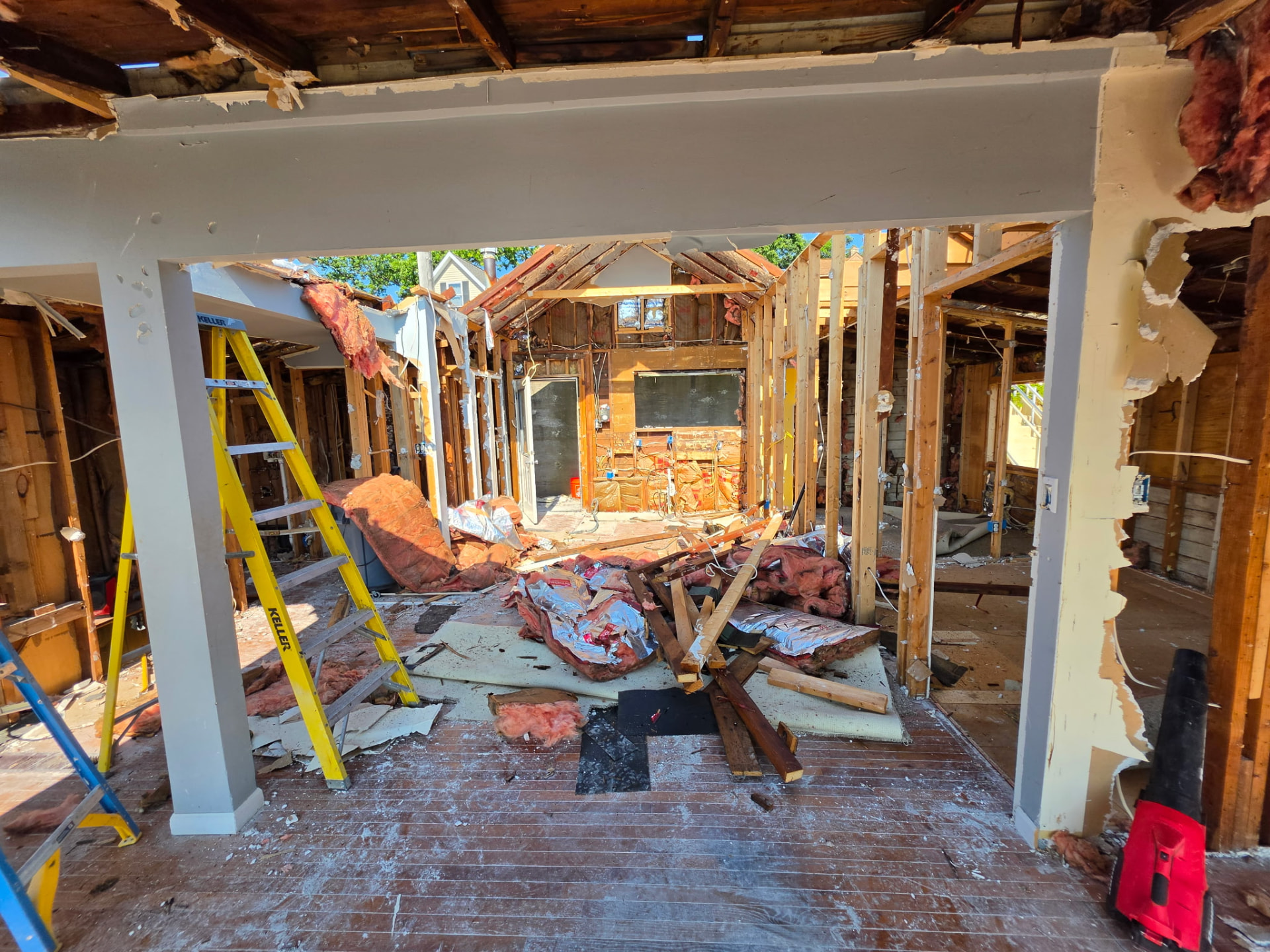 Interior demolition down to the studs during a house tear-down in Brighton, Michigan, with debris ready for a Dumpster Doll roll-off dumpster