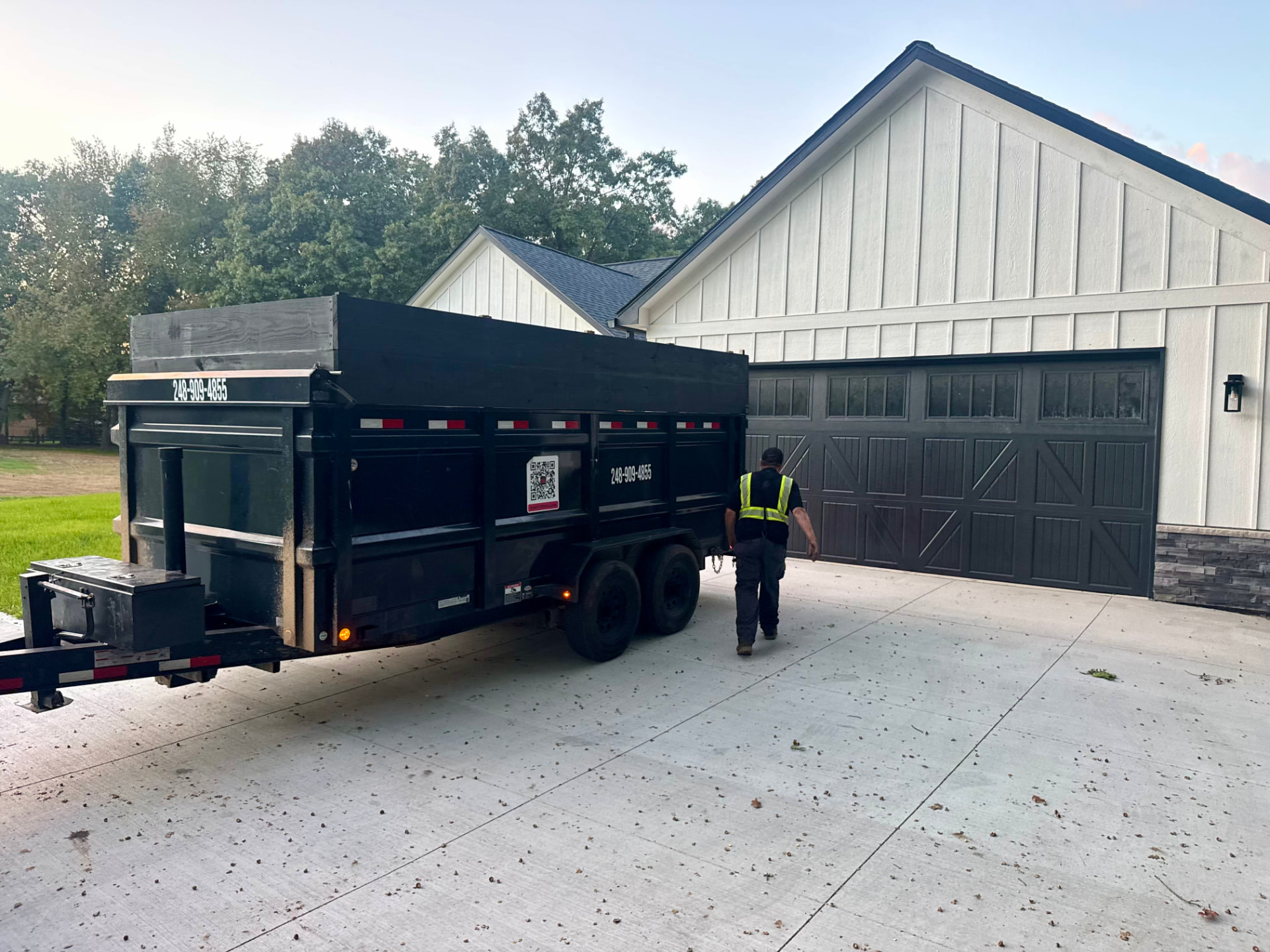 Dumpster Doll driver setting a rubber wheel dumpster trailer in place at a new construction home in Bloomfield Township, Michigan
