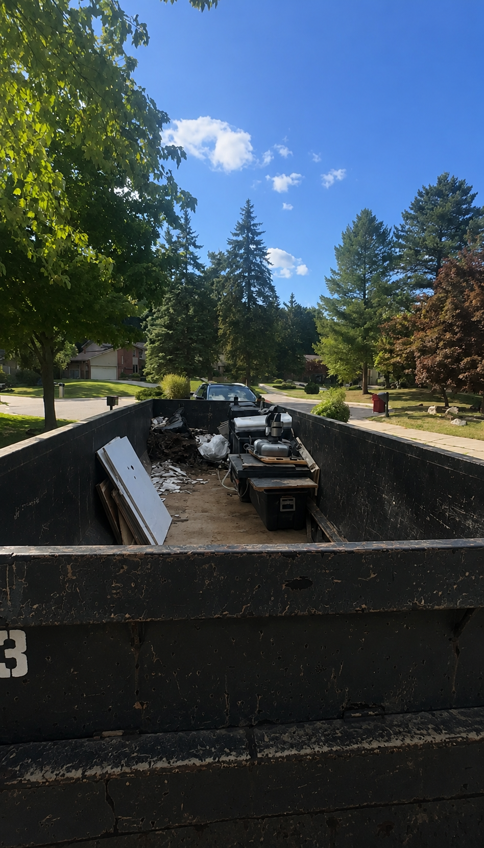 Roll-off dumpster filled with cabinets, drywall and old appliances from a kitchen gut in West Bloomfield, Michigan