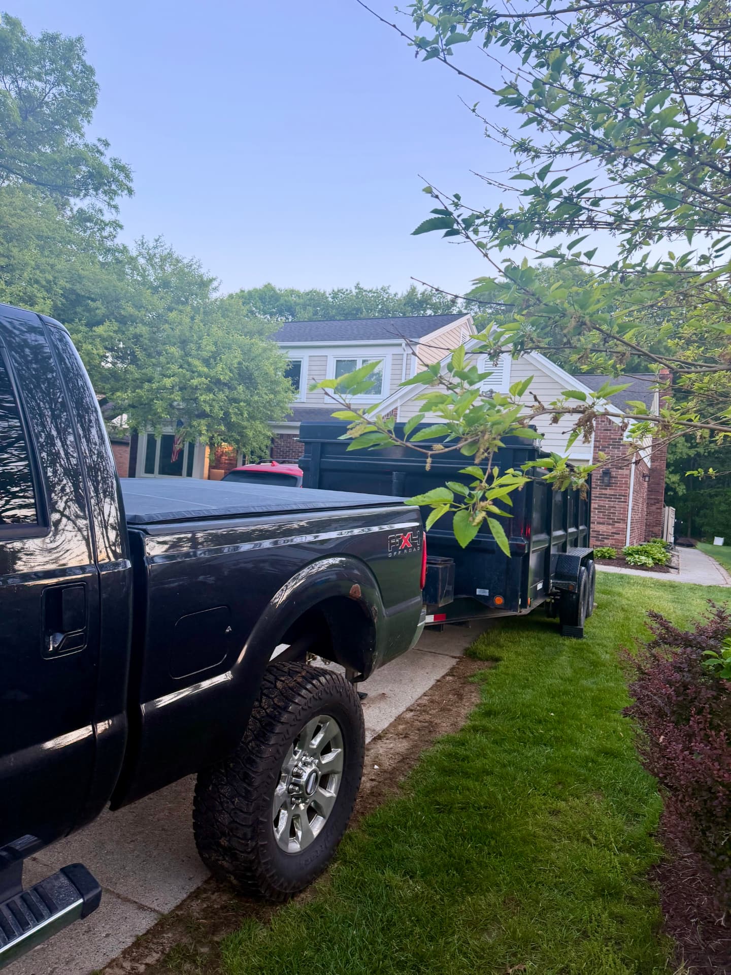 Dumpster Doll truck and rubber wheel dumpster in a residential driveway for a carpet clean out and remodel in Commerce Township, Michigan